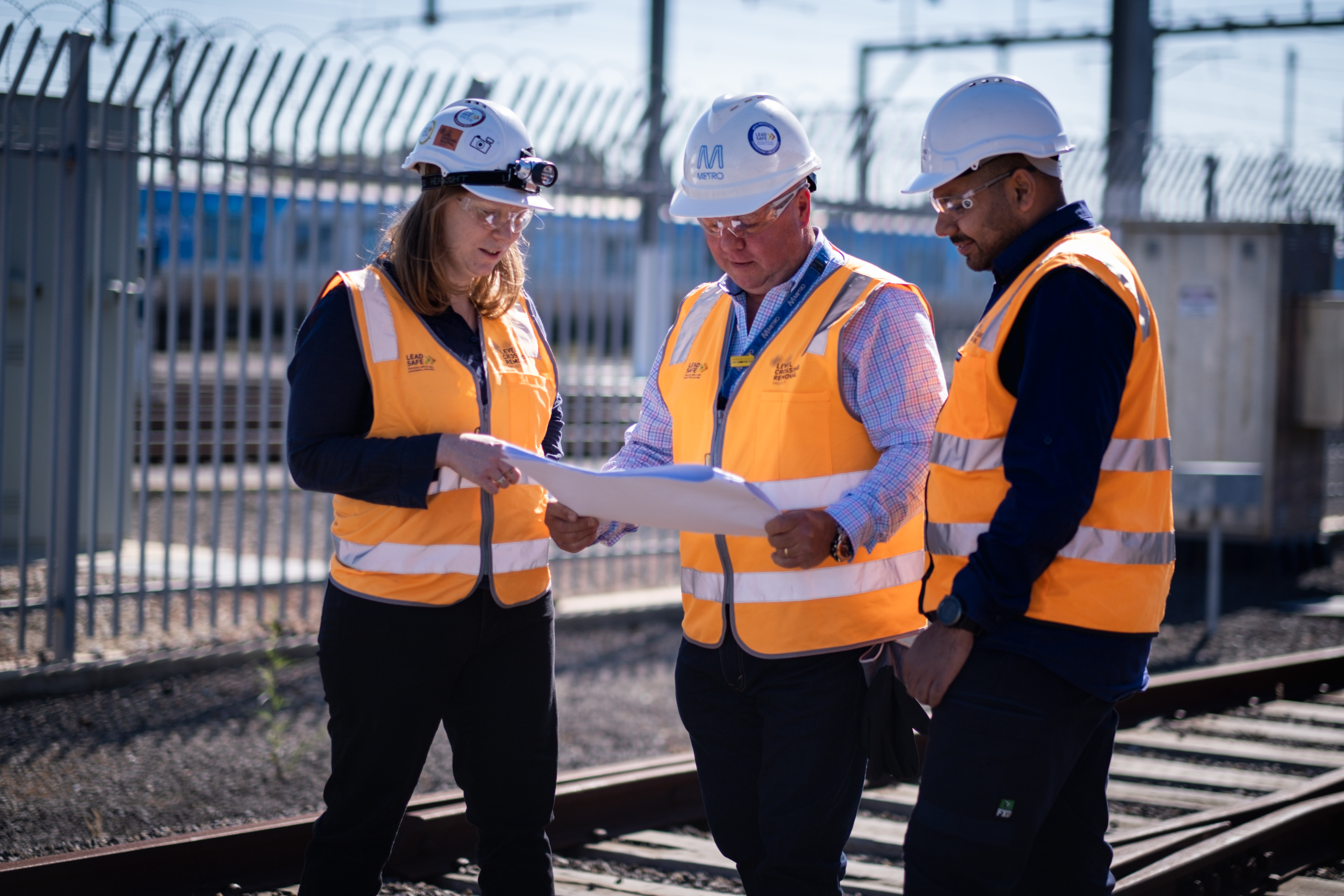 Workers in hats and safety gear looking at map 