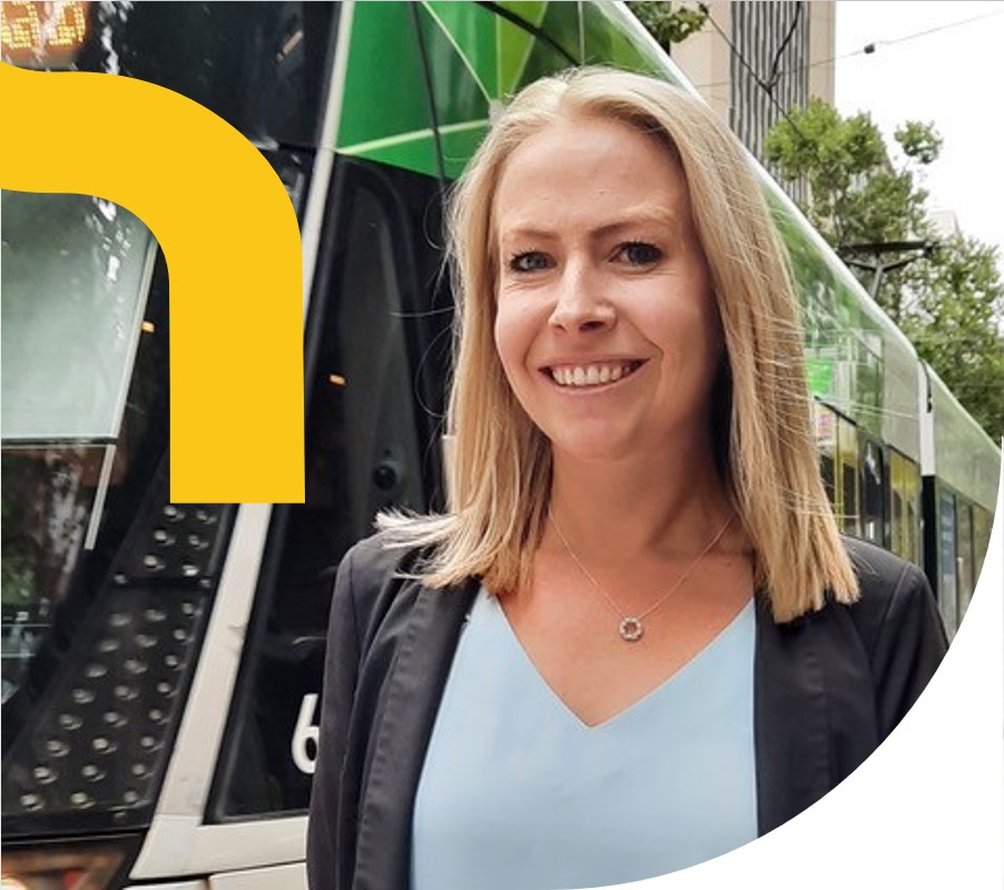 Woman in corporate suit standing beside a tram