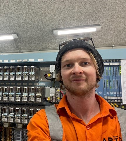 Male signalling technician standing in front of electrical unit