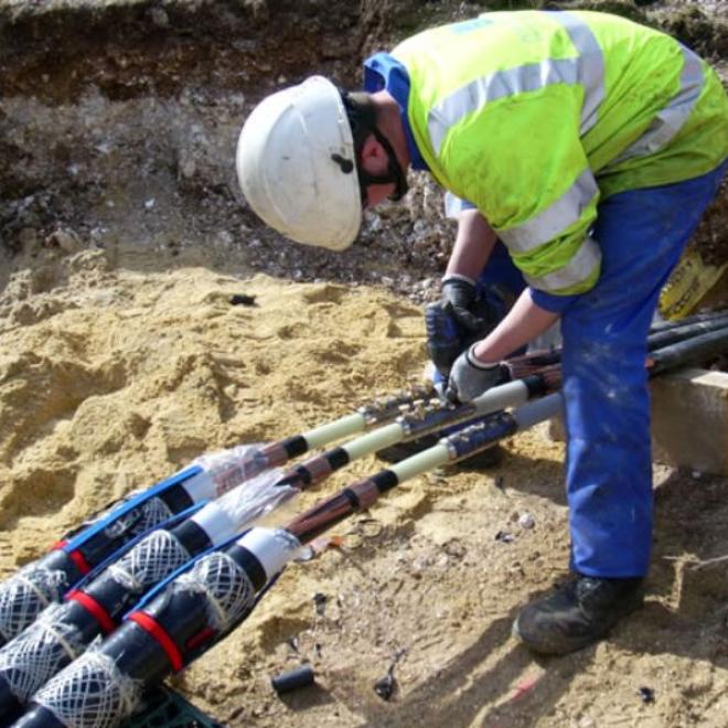 Man in hard hat working on underground electric cable