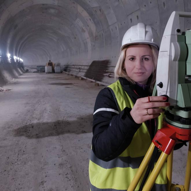 Female land surveyor working on rail tunnel project.