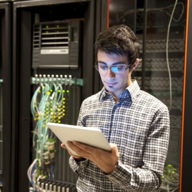 System administrator standing in front of a bank of computer hardware
