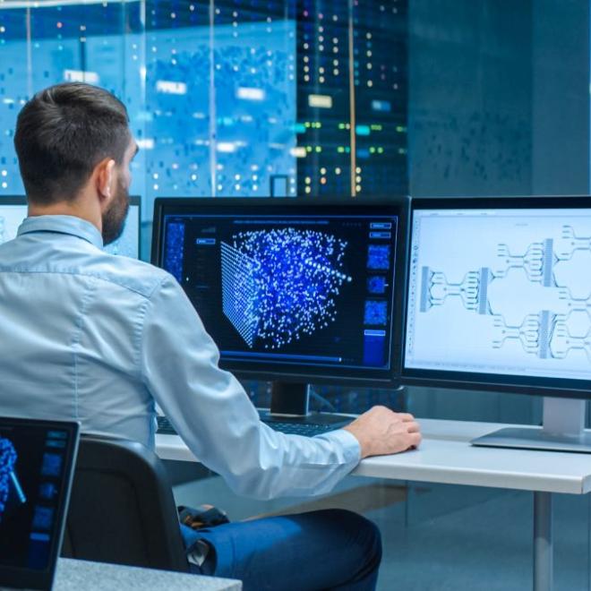 Systems engineer sitting in front of computers showing systems mapped out